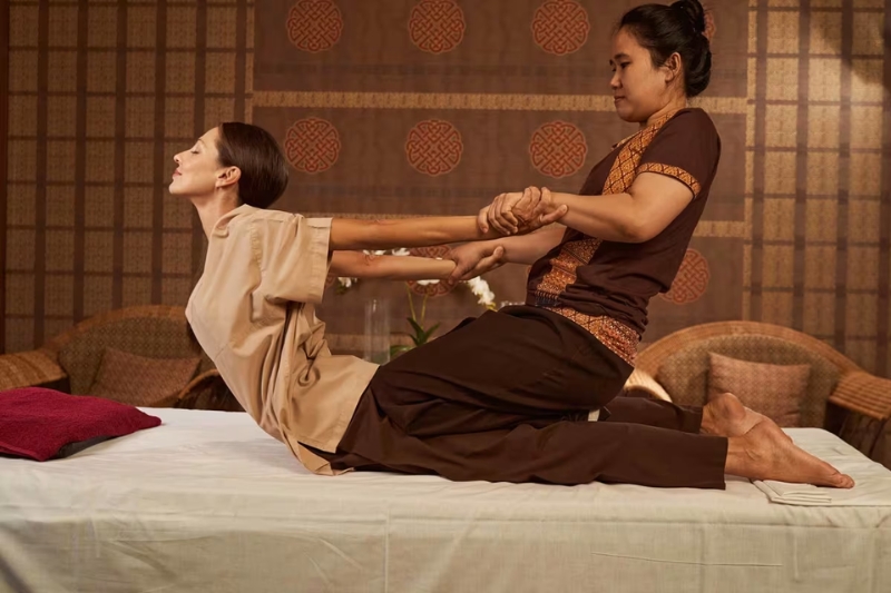 Thai massage therapist stretching a client's body.